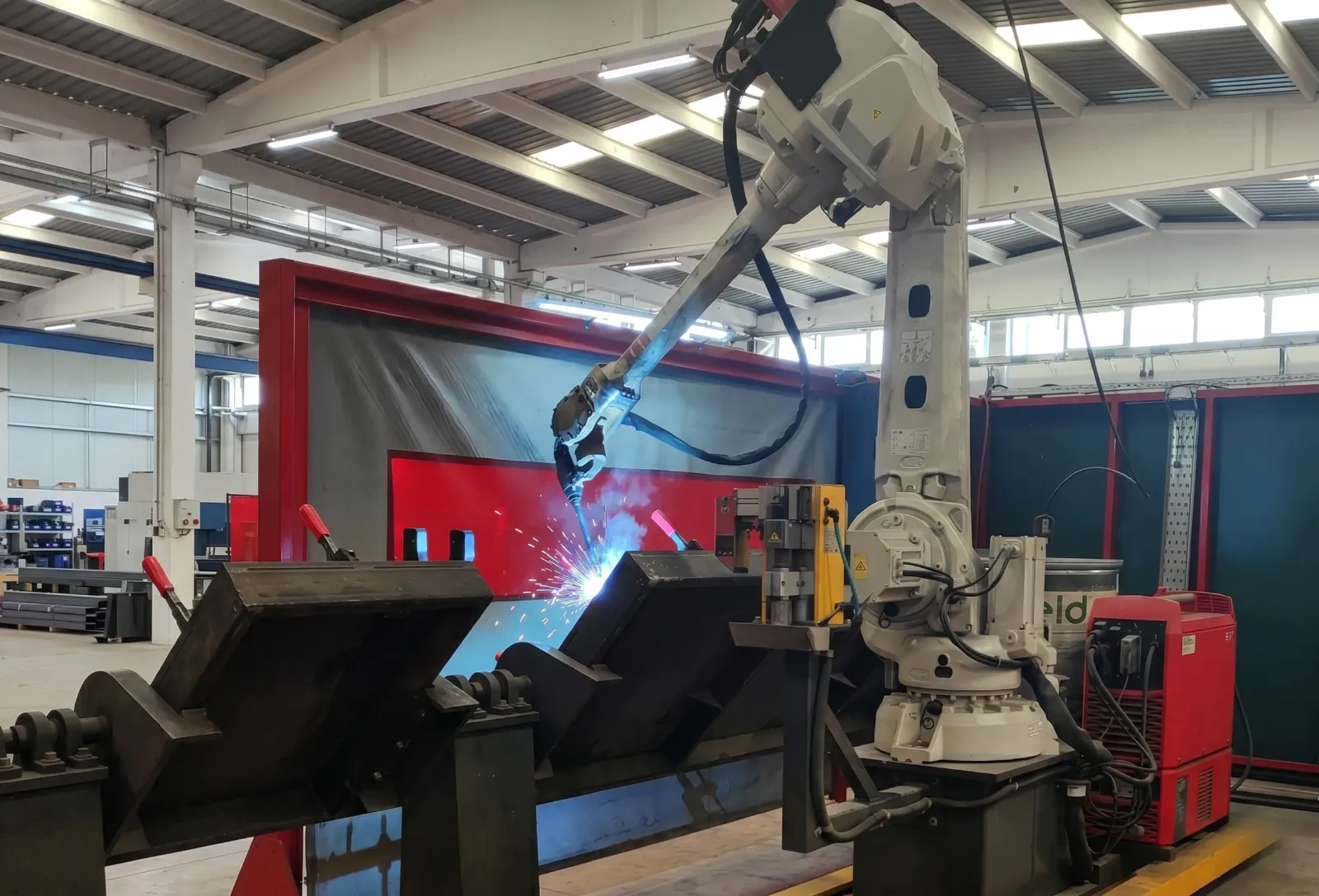 Güvenlik perdesi arkasında kaynak yapan beyaz endüstriyel robot